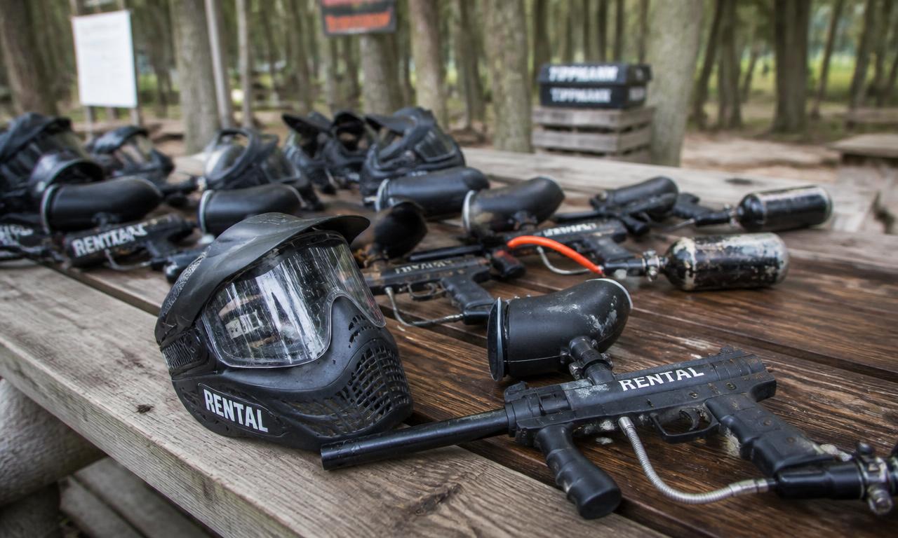 Paintball-varusteita puisella penkillä metsäkentän tukikohdassa.